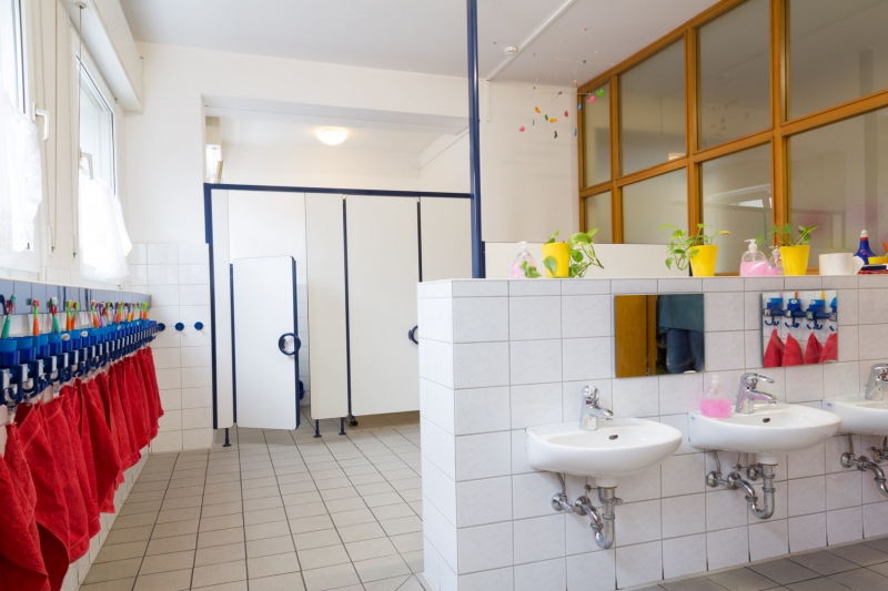 Im Bild sieht man den Waschraum des Altbaus, ausgestattet mit vier Kindertoiletten und sechs Handwaschbecken. Jedes Kind hat seinen eigenen Haken wo seine Zahnbürste steht.